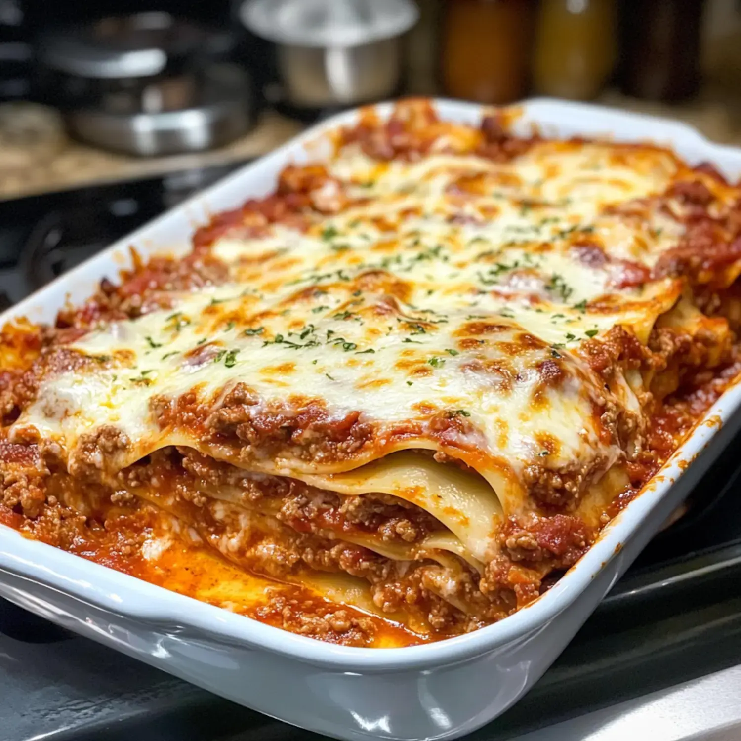 A close-up view of a freshly baked lasagna with layers of pasta, meat sauce, and melted cheese, garnished with herbs.